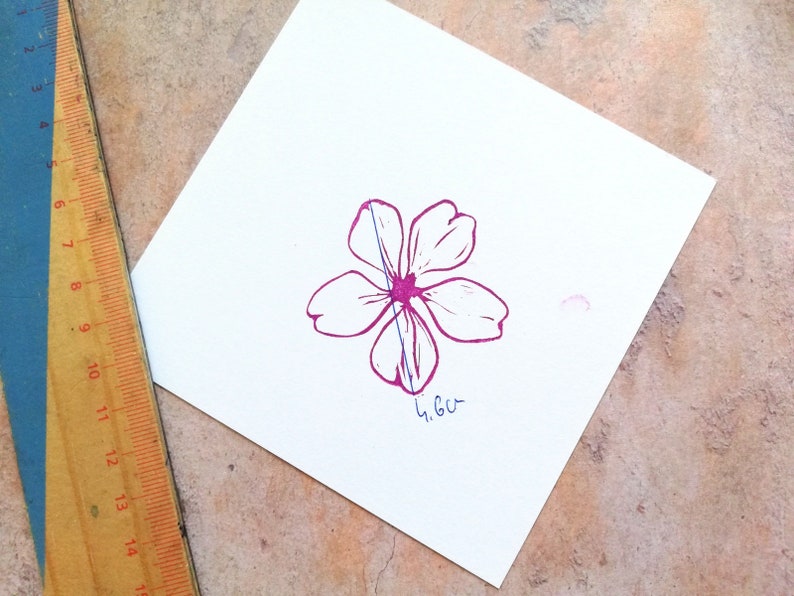 Pode incluir: Uma flor rosa com cinco p&eacute;talas est&aacute; impressa em um peda&ccedil;o de papel branco. Uma r&eacute;gua &eacute; vis&iacute;vel no fundo. A flor tem 4,6 cm de largura.