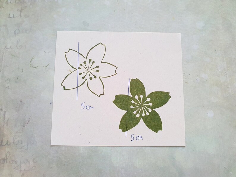 Peut inclure: Deux d&eacute;coupes en papier de fleurs de cerisier, une blanche et une verte, avec des dimensions de 5 cm et 1,5 cm.