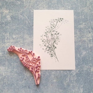 May include: A pink rubber stamp with a detailed floral design. The stamp is used to create a delicate floral pattern on paper.