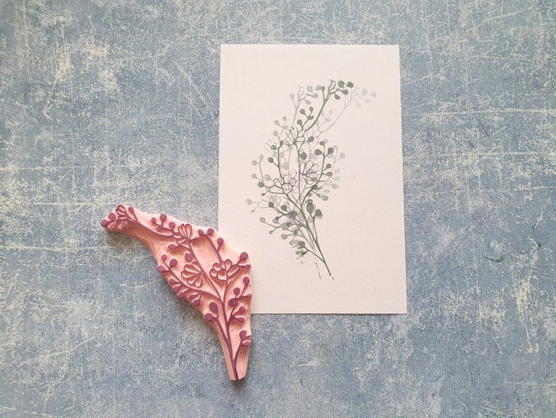 May include: A pink rubber stamp with a detailed floral design. The stamp is used to create a delicate floral pattern on paper.