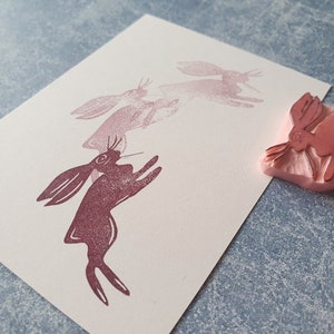 May include: A set of four pink rubber stamps featuring a stylized image of a rabbit in a jumping pose. The stamps are arranged in a line, with the largest stamp at the front and the smallest stamp at the back. The stamps are made of a soft, flexible rubber and are perfect for creating unique and personalized crafts.