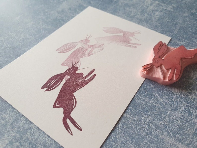 May include: A set of four pink rubber stamps featuring a stylized image of a rabbit in a jumping pose. The stamps are arranged in a line, with the largest stamp at the front and the smallest stamp at the back. The stamps are made of a soft, flexible rubber and are perfect for creating unique and personalized crafts.
