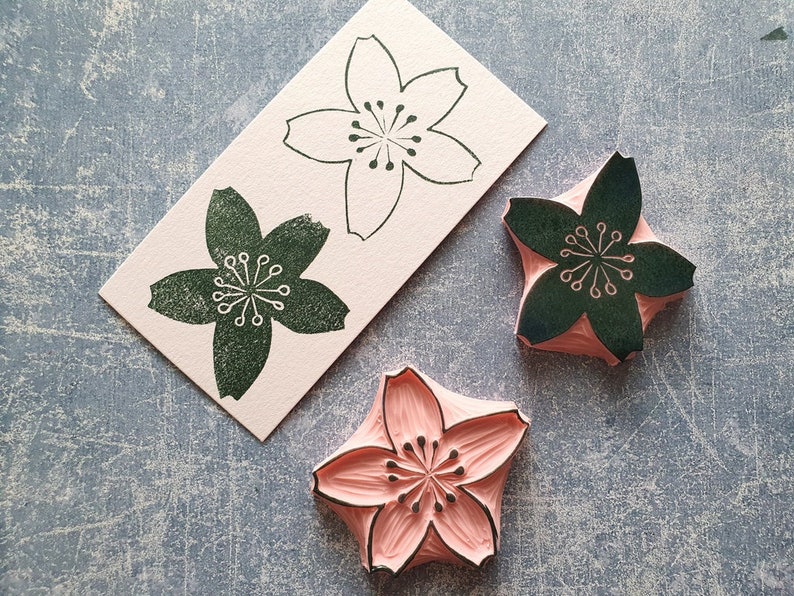 Peut inclure: Trois tampons en forme de fleur de cerisier, un avec une base rose et de l'encre noire, un avec une base blanche et de l'encre noire et un avec une base blanche et de l'encre verte.