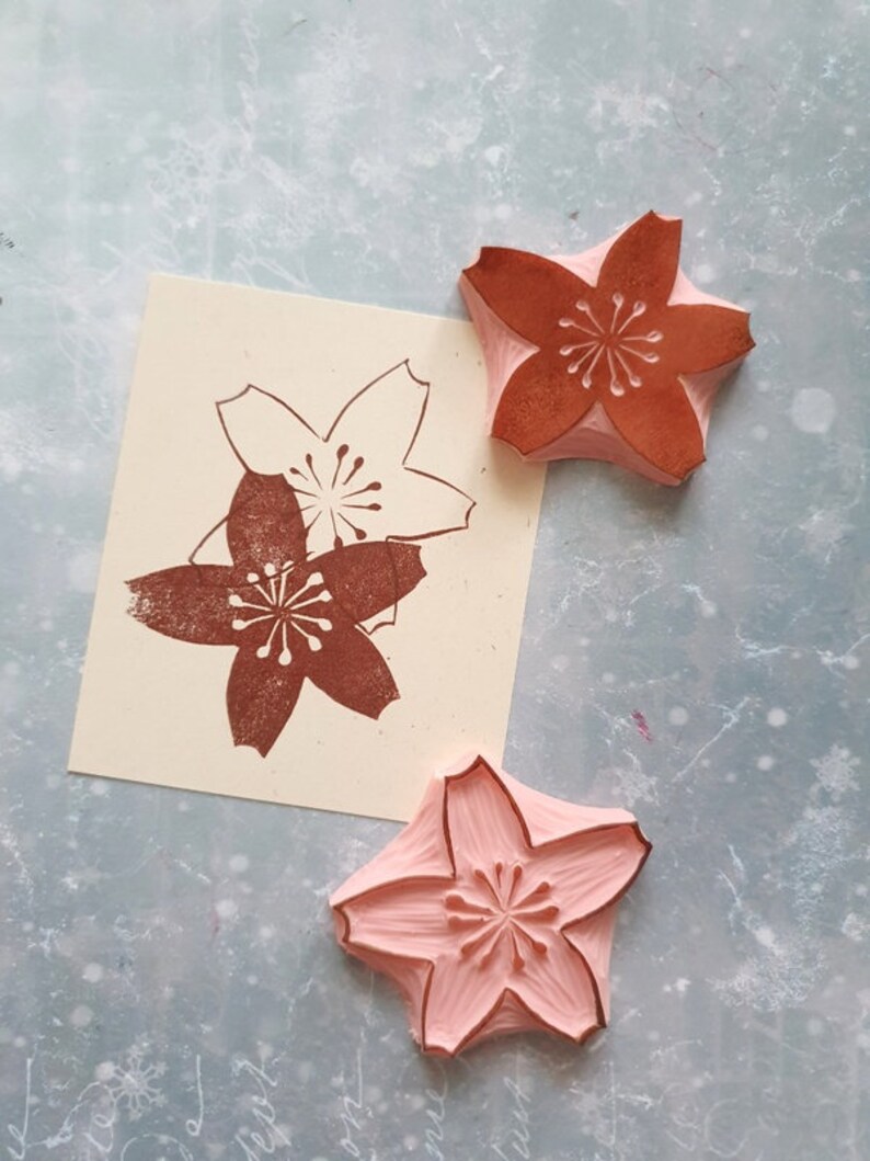 Peut inclure: Trois tampons en bois avec un motif de fleur de cerisier. Deux tampons sont bruns et un est rose.