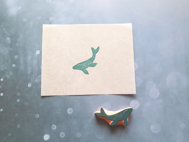May include: A green whale rubber stamp on a white card. The stamp is also shown separately on a light blue background.