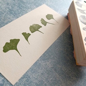 May include: A set of five green rubber stamps featuring different ginkgo leaf designs. The stamps are mounted on wooden blocks.