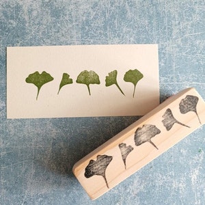 May include: A wooden block with five carved ginkgo leaf shapes. The block is used to create leaf prints on paper.