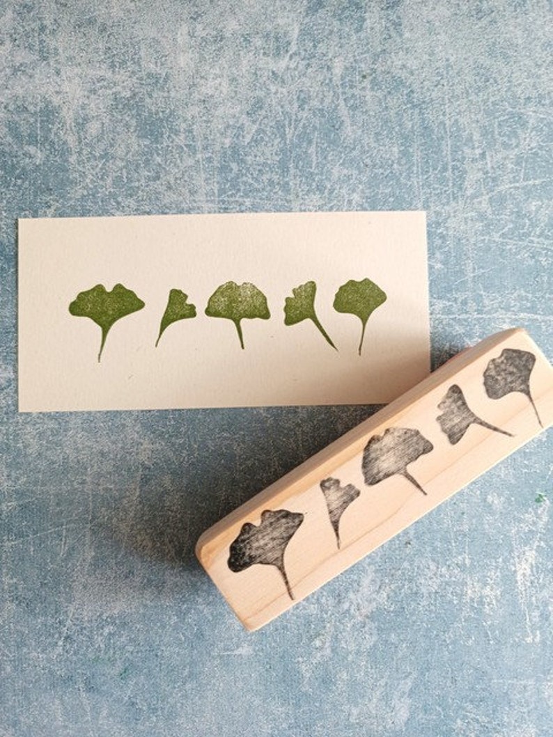 May include: A wooden block with five carved ginkgo leaf shapes. The block is used to create leaf prints on paper.