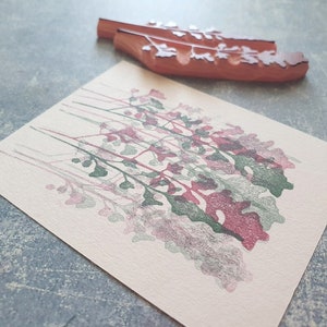 May include: A pink and green floral design stamp print on a cream coloured card.