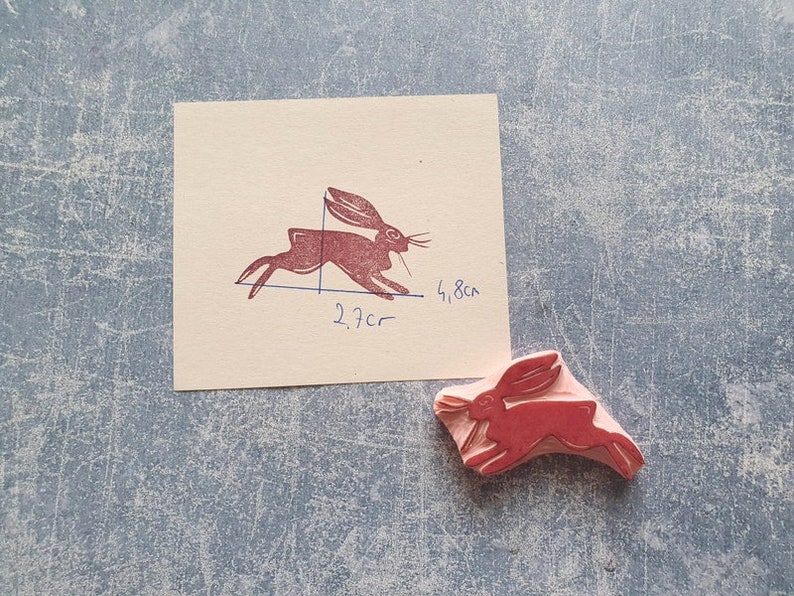 May include: A red rubber stamp of a running rabbit. The stamp is 2.7 inches by 1.8 inches.
