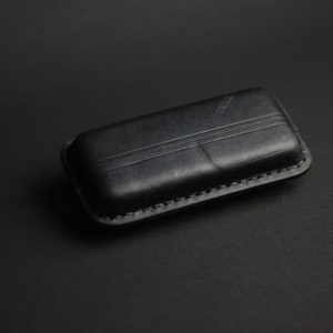 Puede incluir: Una funda de cuero negra con un borde cosido.