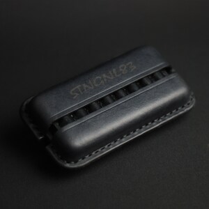 Puede incluir: Una funda de cuero negro con el texto "STENCIL92" grabado en la parte superior. La funda tiene m&uacute;ltiples ranuras para guardar objetos peque&ntilde;os.