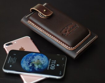 May include: A brown leather phone case with white stitching and a flap closure. The case has the text "WT collection" embossed on the front. A rose gold iPhone is lying on top of the case.