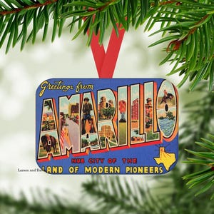 May include: A rectangular Christmas ornament with a blue background and the words "Greetings from AMARILLO" in a vintage postcard style. The ornament features images of Amarillo, Texas, and is suspended by a red ribbon.