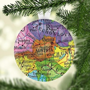 May include: A round, colorful ornament featuring a map of Central Europe with the countries of Austria, Czech Republic, Hungary, and Slovenia labeled. The ornament is a Christmas decoration.