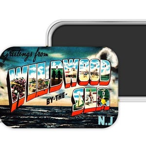 May include: A rectangular magnet featuring a vintage postcard design. The magnet displays the words "Greetings from WILDWOOD BY-THE-SEA N.J." in bold, colorful letters. The background shows a beach scene with ocean waves and a blue sky.