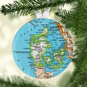 May include: A round, blue and green Christmas ornament featuring a map of Denmark with the text "S DENMARK" and "COPENHAGEN" printed on it.