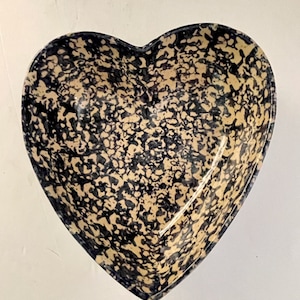 May include: A heart-shaped ceramic bowl with a speckled black and cream glaze.