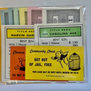 May include: A set of Monopoly game cards, including property deeds for Marvin Gardens and North Carolina Avenue, a Chance card, and a Community Chest card that reads "Get Out of Jail, Free".