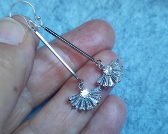 May include: Silver dangle earrings with a fan-shaped design of small clear rhinestones.