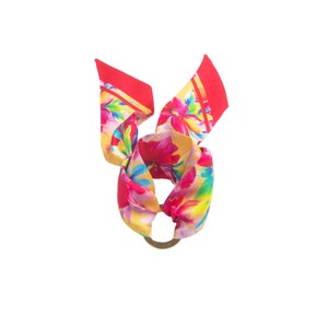 May include: A red, yellow, and pink floral patterned silk scarf tied in a knot with a gold ring.