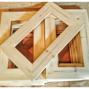May include: A stack of unfinished wooden picture frames. The frames are made of natural wood and have a simple, rectangular design.