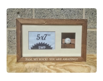 May include: A wooden picture frame with a white mount and a 5x7 inch photo aperture. The frame has a small cutout for a golf ball. The frame is engraved with the text "Pam, my rock! You are amazing!!"