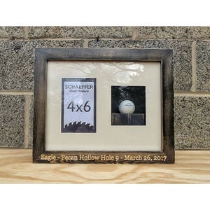 Puede incluir: Un marco de fotos de madera de doble apertura con acabado marr&oacute;n oscuro. Un lado muestra una impresi&oacute;n de 4x6, el otro una pelota de golf. El marco est&aacute; inscrito con "Eagle - Pecan Hollow Hole 9 - March 26, 2017".