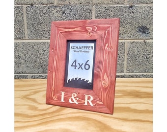 May include: A red wooden picture frame with the text "I & R" engraved on the bottom. The frame is 4x6 inches and has a label that says "Schaeffer Wood Products".