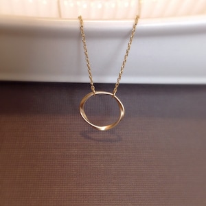 May include: A gold chain necklace with a twisted circle pendant.