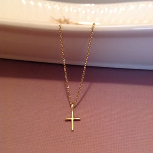 Pu&ograve; includere: Una collana a catena d'oro con un piccolo ciondolo a forma di croce d'oro.