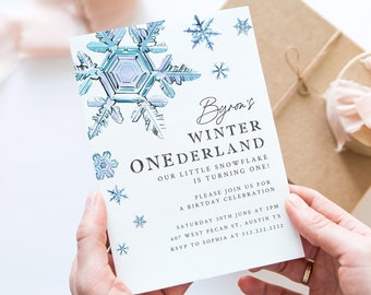 May include: A white invitation card with blue snowflake illustrations and the text "Byron's Winter Onederland Our little snowflake is turning one! Please join us for a birthday celebration Saturday 30th June at 2pm 607 West Pecan St, Austin TX RSVP to Sophia at 512.222.2222"