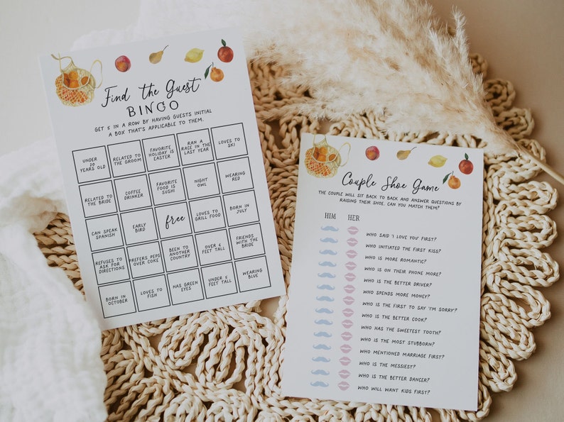 May include: Two printable game cards for a wedding or bridal shower. The first card is a "Find the Guest Bingo" card with a peach, lemon, and pear design. The second card is a "Couple Shoe Game" card with a teapot and fruit design. Both cards have black text.