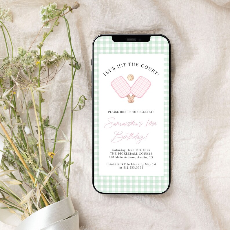May include: A smartphone displays a birthday party invitation. The invitation features pink pickleball paddles and a ball, with the text "LET'S HIT THE COURT!" and "Samantha's 10th Birthday!" on a green gingham background.