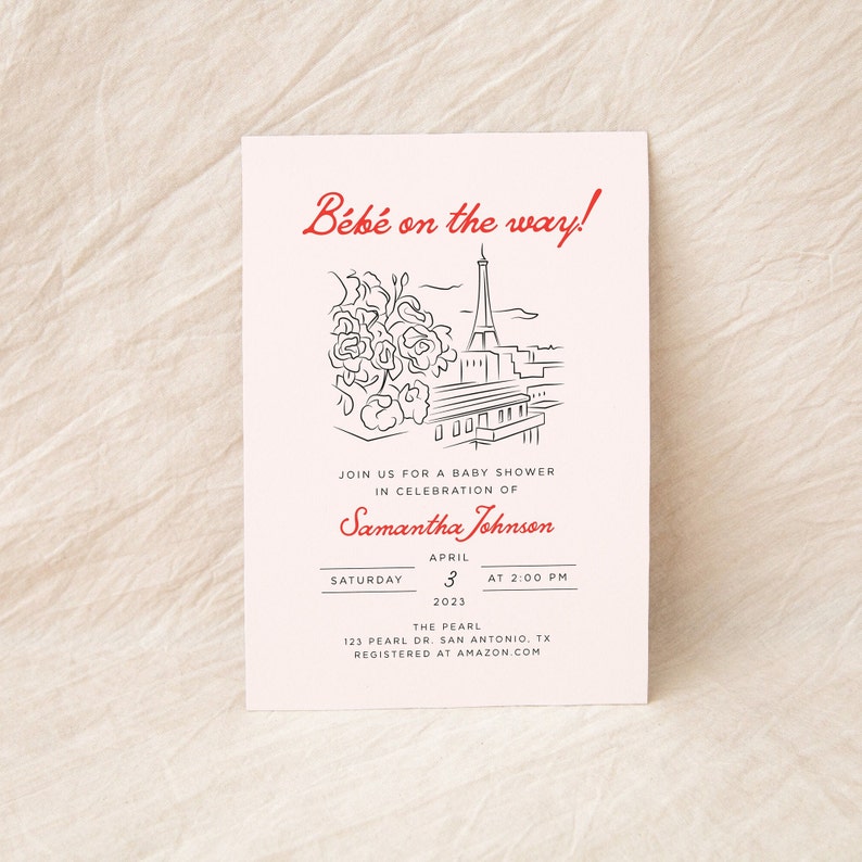 Op de afbeelding: Een witte babyshower-uitnodiging met zwarte en rode tekst. De uitnodiging bevat een lijntekening van de Eiffeltoren en bloemen. De tekst luidt "B&eacute;b&eacute; on the way!" en bevat de datum, tijd en locatie van de babyshower. De uitnodiging bevat ook de naam van de gast van eer, Samantha Johnson, en de registratie-informatie.