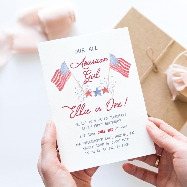 May include: A red, white, and blue invitation card with the text "Our All American Girl Ellie is One!"  Please join us to celebrate Ellie's first birthday! Saturday July 3rd at 1 pm. 123 Firecracker Lane Austin, TX. Kindly RSVP by June 15th to Kelly at 512.555.5555.