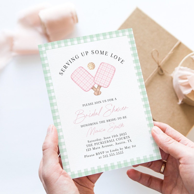 Op de afbeelding: Een groene en witte gingham-gepatroneerde bruidsdoucheinvitatie met roze en witte paddleball-rackets en een bal. De tekst luidt "Serving Up Some Love" en "Please Join Us For A Bridal Shower Honoring The Bride-To-Be Monica Smith Saturday, June 14th 2025 The Pickleball Courts 123 Main Avenue, Austin, TX Please RSVP to Linda by 1 mei at 512.555.5555"
