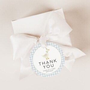 May include: A round blue and white gingham thank you tag with a cartoon goose wearing a green and white hat. The tag says "Thank You" and "Charlie's First Birthday".