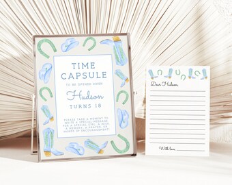 May include: A light blue and green time capsule card with a white background and the text "Time Capsule to be opened when Hudson turns 18". The card is decorated with blue cowboy boots, hats, and horseshoes. A white card with lined paper and the text "Dear Hudson, With love" is next to the time capsule card.