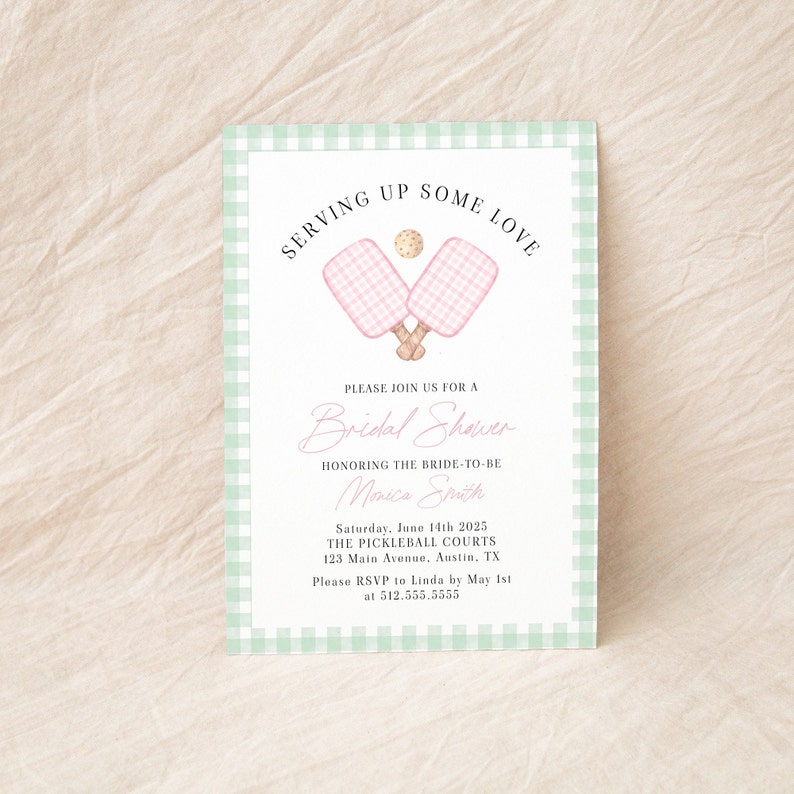 Op de afbeelding: Een groene en witte gingham-gepatroneerde bruidsdoucheinvitatie met een roze en witte gingham-paddle en een roze en witte gingham-bal. De tekst op de uitnodiging luidt "Serving Up Some Love" en "Bridal Shower" ter ere van de aanstaande bruid Monica Smith. De uitnodiging bevat de datum, tijd, locatie en RSVP-informatie.