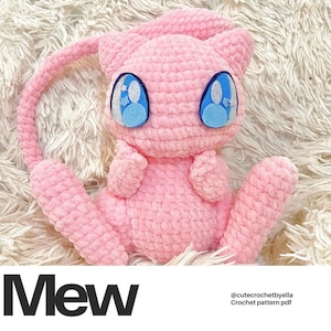 May include: Pink crocheted Mew Pokemon plush toy with blue eyes and a white star on each eye. The plush toy is sitting on a white fluffy surface. The text "Mew" is in black letters at the bottom of the image. The text "@cutecrochetbyella Crochet pattern pdf" is in black letters at the bottom right of the image.