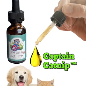 May include: A brown glass bottle with a dropper filled with yellow hemp seed oil for pets. The bottle label says "Captain Catnip" and "Hemp Seed Oil" with a cartoon cat wearing a superhero costume. A golden retriever puppy and a ginger cat are sitting in the foreground.