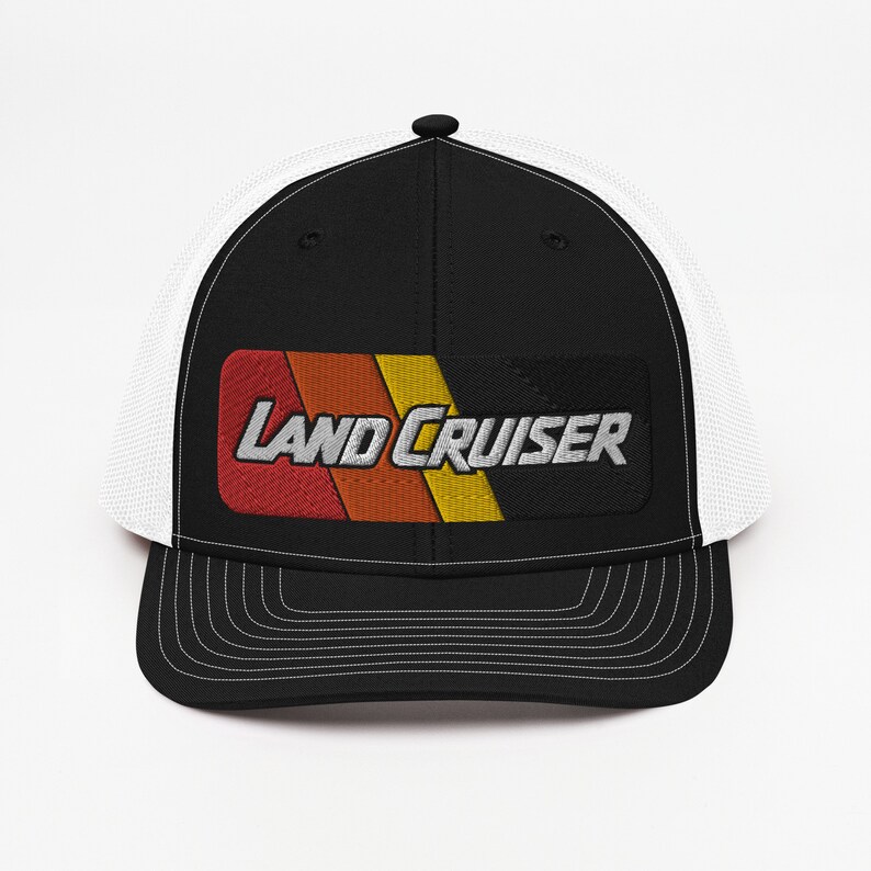 Puede incluir: Gorra de camionero negra y blanca con un parche bordado en rojo, naranja, amarillo y negro que dice "LAND CRUISER" en blanco.