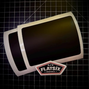 May include: Two black rectangular stickers with rounded corners and a white border are stacked. A white and red logo with the text "FLATSIX GRAPHICS" is below the stickers.