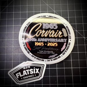 Puede incluir: Dos pegatinas sobre una superficie de cuadrícula negra. La pegatina redonda más grande conmemora el 60 aniversario del Corvair de 1965, con texto como "Still Revolutionary" y números de producción. La pegatina más pequeña muestra "FLATSIX GRAPHICS".