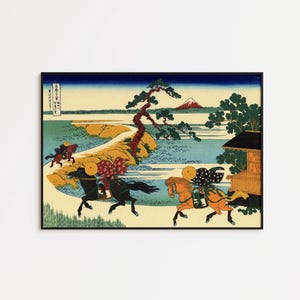 May include: Framed Japanese woodblock print depicting riders on horseback. The artwork features a landscape with a mountain, a lake, and a building. The riders are wearing traditional attire, and the print has a black frame.