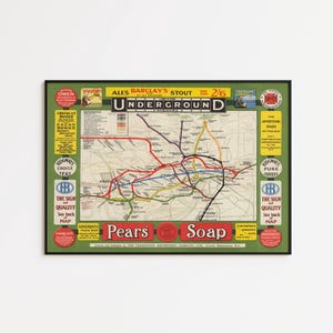 May include: Vintage London Underground map print in a black frame. The map features a network of colorful lines representing the tube lines, with advertisements for Pears Soap and other products. The print measures approximately 24 x 18 inches.