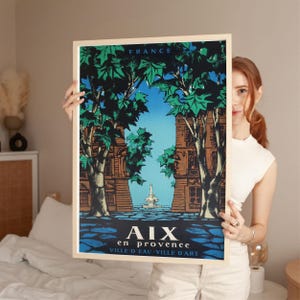May include: A framed travel poster for Aix-en-Provence, France, depicting a street scene with trees and buildings. The poster has a blue sky, green foliage, and the text "AIX en PROVENCE VILLE D'EAU VILLE D'ART".