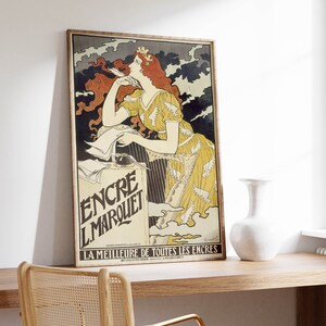 May include: A vintage poster advertising "Encre L'Marquet" ink. The poster features a woman with flowing red hair, wearing a yellow dress with white wings, against a backdrop of dark clouds. The text "LA MEILLEURE DE TOUTES LES ENCRES" is at the bottom of the poster.