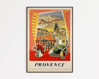Può includere: Un poster di viaggio vintage incorniciato per la Provenza, Francia, con un paesaggio visto attraverso una finestra. Il poster include una natura morta con un vaso di fiori e una ciotola di frutta. Il testo recita "PROVENCE".